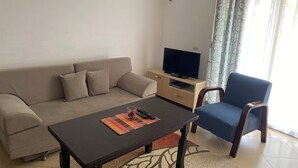 Una sala de estar con un sofá, una mesa de centro, un televisor y una silla.