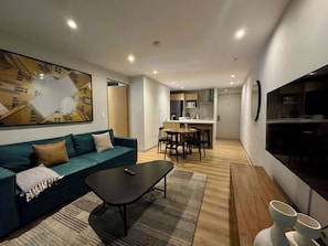 A modern living room with a sofa, coffee table, and a dining area with chairs and a table. - w* | Welcoming 1BR w/ AC in the Heart of Roma Sur (Ciudad de México)