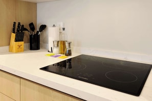 A kitchen with a black induction cooktop, a knife block, a spice rack, and a white countertop. - w* | Welcoming 1BR w/ AC in the Heart of Roma Sur (Ciudad de México)