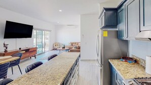 A modern kitchen with granite countertops, a built-in oven, and a flat-screen TV mounted above the counter. - Luxurious Mountain-view Apartment Close to the sea With Rooftop Sunset Views (Cabo San Lucas)