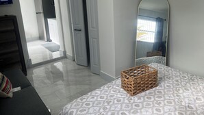 A bedroom with a bed, a mirror, a dresser, and a television in the adjacent room.