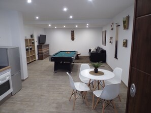 Ein Zimmer mit Pooltisch, einer Couch, einem Fernseher und einem Essbereich mit Stühlen.