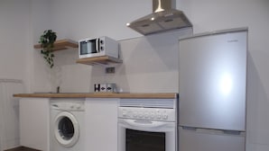 Une cuisine compacte équipée d’un lave-linge, d’un four, d’un four à micro-ondes et d’un réfrigérateur encastré.