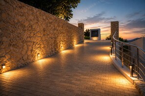Un muro de piedra, un sendero pavimentado y un edificio de diseño moderno.
