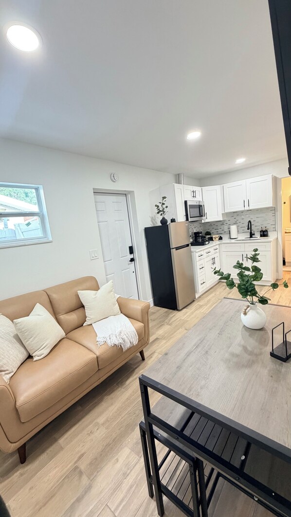 A modern kitchen with white cabinets, a black refrigerator, and a dining area with a wooden table and chairs.