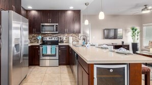 A modern kitchen with stainless steel appliances, a large island, and a flat-screen TV. - Toscana Treasure! Cozy 2-bedroom condo with lots of amenities in Phoenix! (Phoenix)