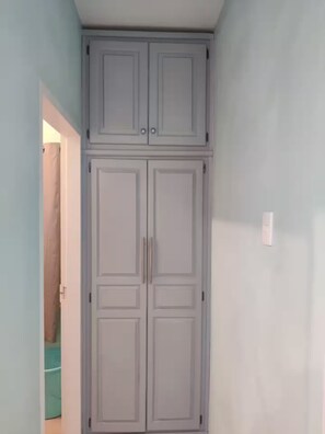 Ein Flur mit Doppeltür, Lichtschalter und teilweise sichtbarem Badezimmer mit Duschvorhang.