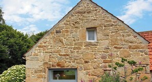 Ein Steinhaus mit einem dreieckigen Dach, einem kleinen Fenster und einer Tür.