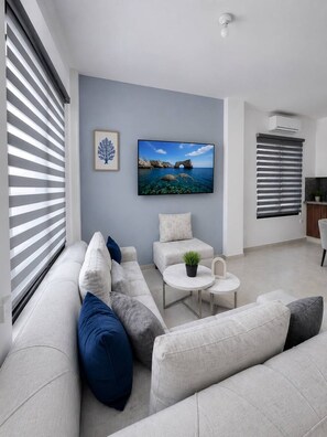 A modern living room with a sofa, a small table, and a TV mounted on the wall. - MARLIN (San Cristobal)