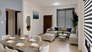 A modern living room with a dining area, featuring a sofa set, a coffee table, and a dining table set for six. - MARLIN (San Cristobal)