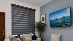 Un salon comprenant un canapé, une table basse, une plante en pot et un tableau encadré accroché au mur.