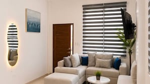 Un salon moderne comprenant un ensemble de canapés, une table basse et un coin repas avec une table dressée pour deux personnes.