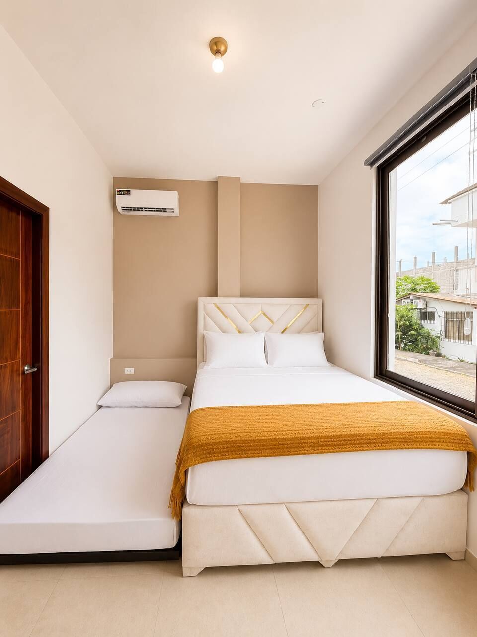 Een slaapkamer met een bed, een raam, een airconditioning en een deur.