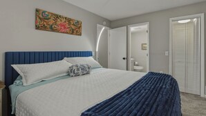 Een slaapkamer met een bed, nachtkastje, deur en inloopkast.