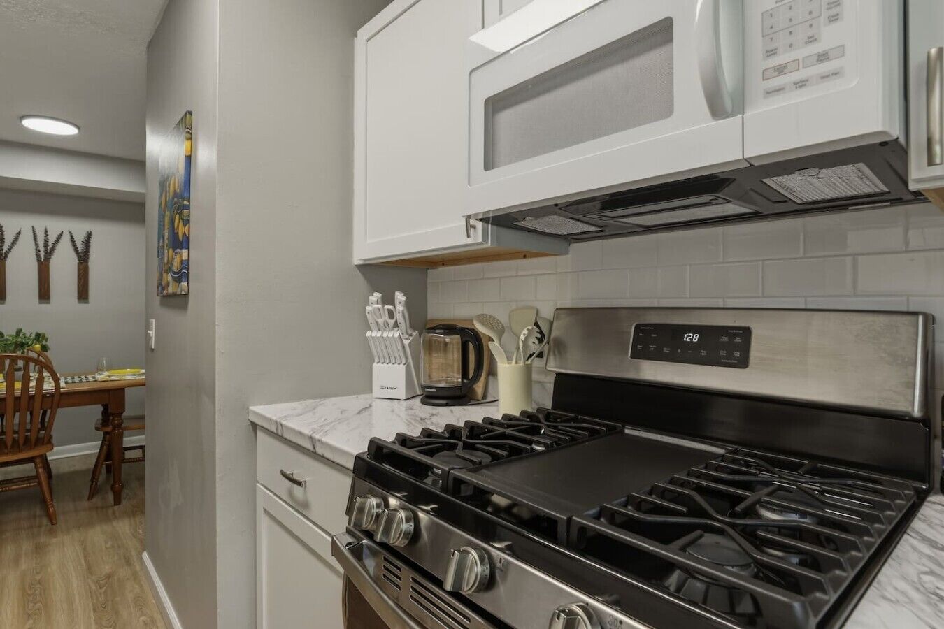 A kitchen with a gas stove, microwave, and stainless steel cabinets.