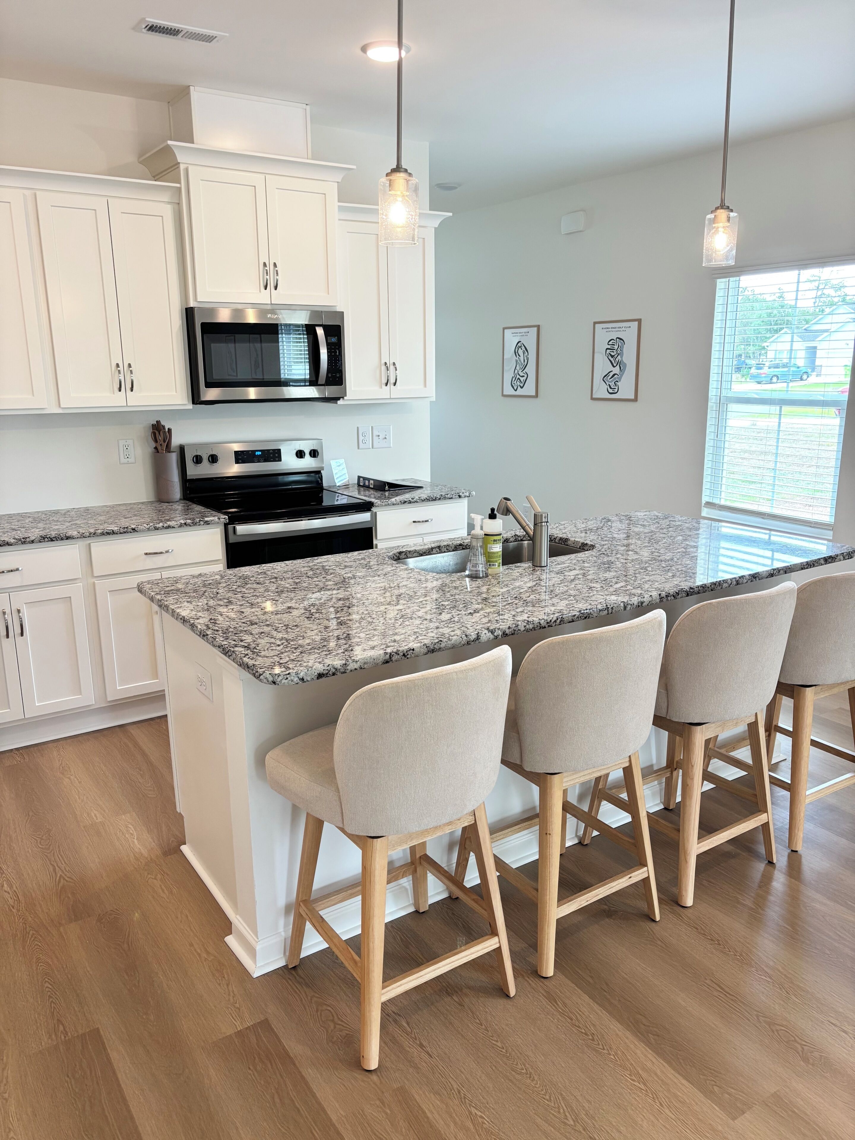 A modern kitchen with white cabinets, a granite countertop, a built-in microwave, and a stainless steel stove.