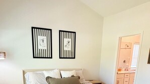 A bedroom with a bed, two nightstands, a bedside lamp, and a door leading to a bathroom. - Golf + Beach stay w/ private putting green! (Shallotte)
