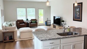 A spacious living area with a large island kitchen, a television, and a framed poster on the wall. - Golf + Beach stay w/ private putting green! (Shallotte)