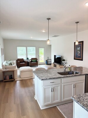 A spacious living area with a large island kitchen, a television, and a framed poster on the wall. - Golf + Beach stay w/ private putting green! (Shallotte)
