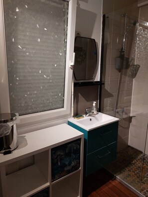 A bathroom with a window, a sink, a mirror, and a shower. - townhouse (plouezec)