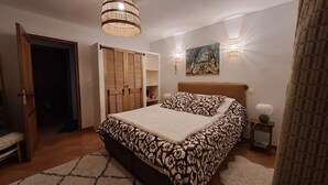 A bedroom with a bed, a wardrobe, a painting, and two wall sconces. - Provençal villa with a private pool, shaded garden terrace, quiet location, and parking (Arles)