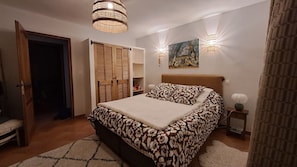A bedroom with a bed, a wardrobe, a painting, and two wall sconces. - Provençal villa with a private pool, shaded garden terrace, quiet location, and parking (Arles)