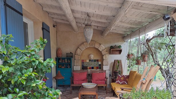 A rustic outdoor seating area with wooden furniture, a tiled floor, and a stone archway. - Provençal villa with a private pool, shaded garden terrace, quiet location, and parking (Arles)