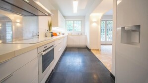 Una cocina moderna con armarios blancos, piso de baldosas negras y un ventanal que proporciona luz natural.