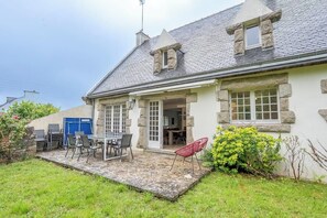Ein Steinhaus mit Terrasse, Esstisch und Stühlen.