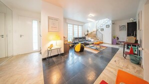 Amplia sala de estar con una escalera, un sofá, una mesa de centro y una lámpara.