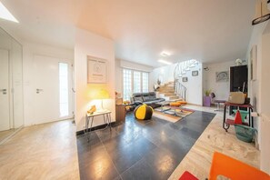 Een ruime woonkamer met een trap, een bank, een salontafel en een lamp.