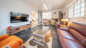 Una sala de estar moderna con un televisor de pantalla plana, un sofá de cuero, una mesa de centro y un mueble para la televisión.