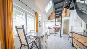 Una cocina moderna con comedor, una escalera y vistas al exterior.