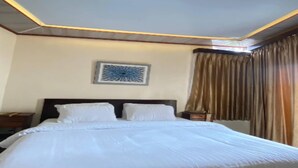 Une chambre d’hôtel avec un grand lit, un luminaire au plafond et une œuvre d’art accrochée au mur.