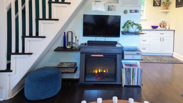 A living room with a fireplace, a television, and a staircase. - Artist's bungalow and garden in SE Portland (Milwaukie)