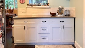 A kitchen with white cabinets, a window, and a countertop with kitchen appliances. - Artist's bungalow and garden in SE Portland (Milwaukie)