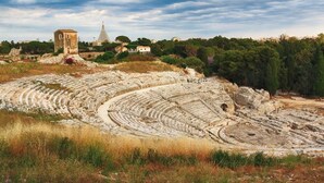 An ancient amphitheater with tiered seating and a central stage. - GEA Guest House (Syracuse)