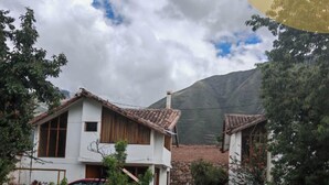 A rural house with a tiled roof, surrounded by greenery and a mountain in the background. - Umay Lodge: A House in the Mountains (Urubamba)