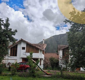 A rural house with a tiled roof, surrounded by greenery and a mountain in the background. - Umay Lodge: A House in the Mountains (Urubamba)