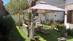 A covered outdoor seating area with wicker furniture, a hammock, and potted plants. - Umay Lodge: A House in the Mountains (Urubamba)