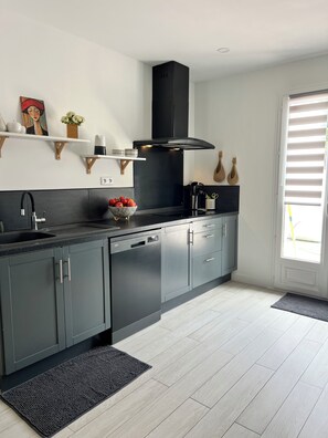 A modern kitchen with grey cabinets, a black range hood, and a black dishwasher. - Charming house & pool between Aix / Marseille (Gardanne)