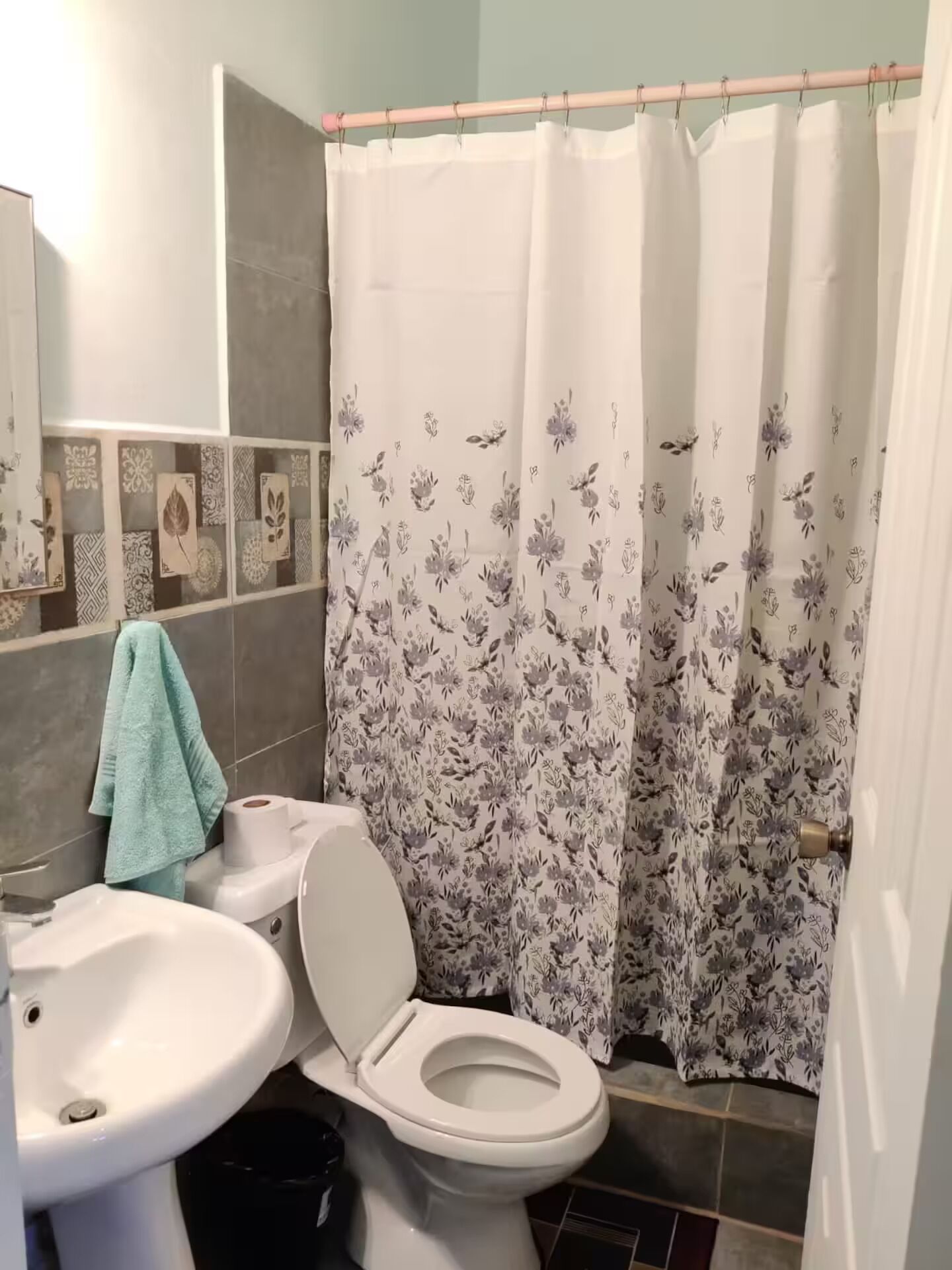 Un baño con inodoro, lavamanos y cortina de ducha.