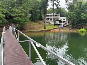 A wooden pier leading to a building with a balcony, surrounded by trees and a body of water. - Family. Porches. Pets. Smith Lake. "Just Heavenly" (Arley)