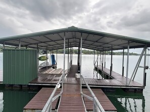 A covered dock with a metal roof, wooden planks, and a green metal building nearby. - Family. Porches. Pets. Smith Lake. "Just Heavenly" (Arley)