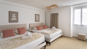 Quarto de hotel com duas camas, uma janela grande e um lustre.