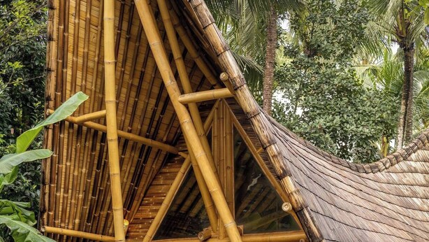 A bamboo structure with a thatched roof, two lounge chairs, and a pool. - Cacao House Eco-luxe Family Home Near Green School (Abiansemal)