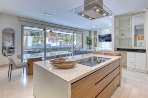 A modern kitchen with a large island, built-in appliances, and a view of the outdoor area. - Peaceful Condo With Resort Pool, High-speed Wifi & Relaxing Outdoor Space (Cabo San Lucas)