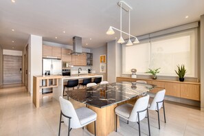 A modern kitchen with a central island, built-in appliances, and a large window providing natural light. - Peaceful Condo With Resort Pool, High-speed Wifi & Relaxing Outdoor Space (Cabo San Lucas)