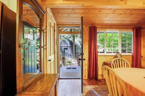Ein Holzinterieur mit einem Bett, einem Esstisch und Blick ins Freie.