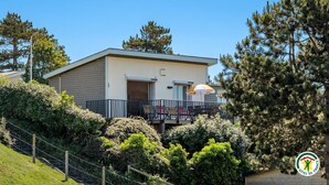A modern two-story building with a balcony, surrounded by greenery and trees. - Gîtes de France® - La Villa Pomponette (CRIEL SUR MER)